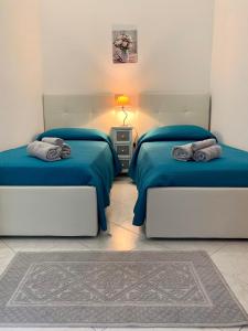 een slaapkamer met 2 bedden met blauwe lakens en een tapijt bij I Limoni del Sud Sardegna in Assemini