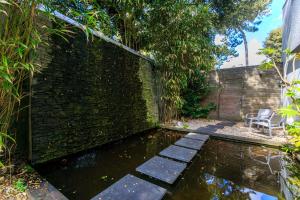 un jardin avec un étang en face d'un mur de briques dans l'établissement Best Western Hôtel Garden and Spa, à La Baule