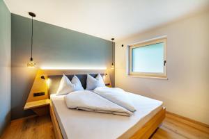a bedroom with a white bed with a window at Aktiv Lodge Meran - Terrace One in Saltusio