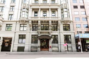 a large white building on the corner of a street at Rendezvous Hotel Melbourne in Melbourne