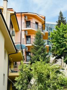 un edificio de apartamentos con árboles delante de él en Villa Mari Guest Rooms, en Golden Sands