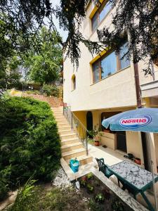 a house with a table and an umbrella and stairs at Villa Mari Guest Rooms in Golden Sands