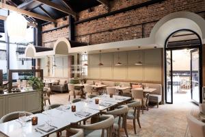 a restaurant with tables and chairs and a brick wall at Adina Apartment Hotel Melbourne, Pentridge in Melbourne