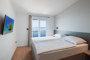 a white bedroom with a large bed with a window at Apartmani Stipe Brela in Brela