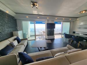 a living room with a couch and a dining room with a table at LE COLOMBIER T3 VUE MER PANORAMIQUE in Antibes