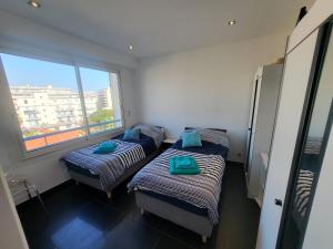two beds in a room with a large window at LE COLOMBIER T3 VUE MER PANORAMIQUE in Antibes