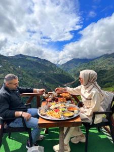 a man and woman sitting at a table with a plate of food at Zifona Bungalov in Çamlıhemşin