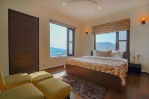 a bedroom with a bed and a couch and windows at SaffronStays Summer Estate in Kasauli