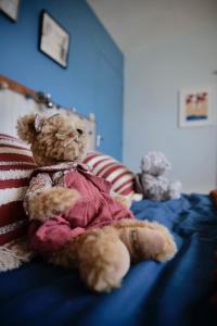 a brown teddy bear sitting on a bed at Chambre privée dans Maison Familiale in Veyrier-du-Lac