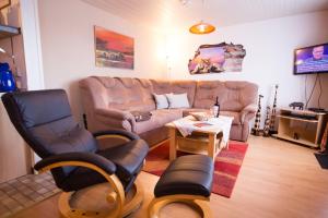 ein Wohnzimmer mit einem Sofa, Stühlen und einem Tisch in der Unterkunft Haus Karin Ferienwohnung 1 in Büsum