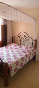 a bedroom with a bed with a floral bedspread at L'auberge Homestay in Nairobi