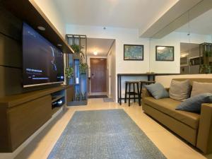 a living room with a couch and a flat screen tv at Luxury Condo with Pool View at Shell Residences in Manila