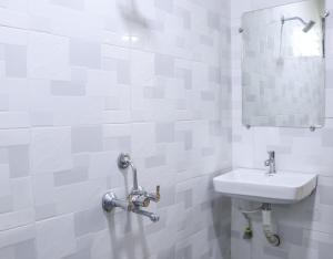 a white bathroom with a sink and a mirror at Hotel Mukesh Residency in Pune