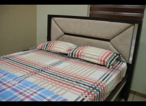 - un lit avec une couette rayée et 2 oreillers dans l'établissement Zenith Homes, à Elūr