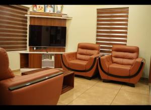 - un salon avec deux chaises et une télévision à écran plat dans l'établissement Zenith Homes, à Elūr