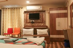 a hotel room with a bed and a flat screen tv at Hotel Mukesh Residency in Pune