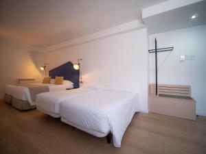 a bedroom with two beds and a cross on the wall at Hotel Roc Meler in Canillo