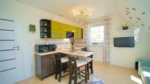 a kitchen with yellow cabinets and a table and chairs at Apartamenty Every Sky Nad Łomnicą 1b-6b in Karpacz