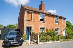 a car parked in front of a brick house at Hall Cottage Bramfield Suffolk in Bramfield