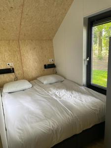 Cama blanca en habitación con ventana en EuroParcs De Wiedense Meren, en Wanneperveen