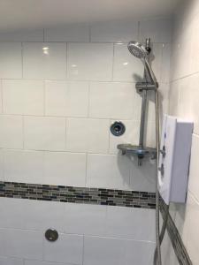 eine Dusche in einem weiß gefliesten Bad in der Unterkunft Self contained annex in Bournemouth