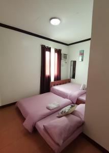 SilangにあるRachel’s Bed and Breakfastのピンクのシーツが備わる客室内のベッド2台