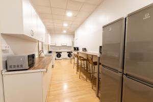 una cocina con armarios blancos y electrodomésticos de acero inoxidable en Live it Madrid Gran Vía, en Madrid