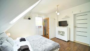 a white bedroom with a bed and a tv at Apartamenty Every Sky Nad Łomnicą 1b-6b in Karpacz +2 photos