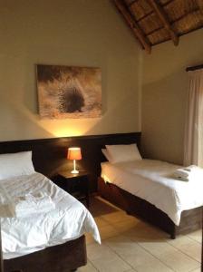 sypialnia z 2 łóżkami i obrazem na ścianie w obiekcie Matalatala Wildlife Lodge w mieście Roodeplaat