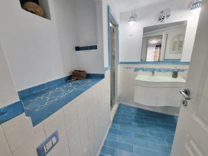 e bagno con lavabo e piastrelle bianche e blu. di Maridea - Medusa a Ponza