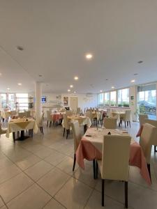 a dining room with tables and chairs and windows at Eden Hotel in Deiva Marina