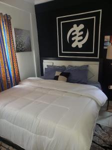 um quarto com uma grande cama branca com almofadas azuis em KESEWAA's APARTMENT em Acra
