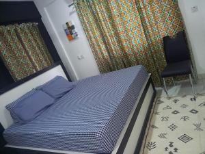 łóżko z niebieskimi poduszkami i krzesłem w pokoju w obiekcie KESEWAA's APARTMENT w Akrze