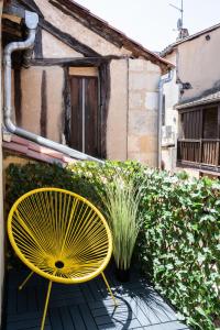 a yellow chair sitting on a patio next to a building at Redbrick’s Bergerac, Au coeur du centre historique in Bergerac