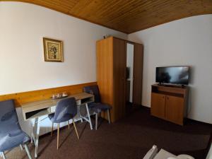 a room with a table and chairs and a television at Pension Casa Samurai in Braşov