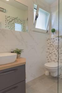 La salle de bains est pourvue d'un lavabo, de toilettes et d'un miroir. dans l'établissement Cozy Apartment - 100m from the beach Punta, à Pakoštane