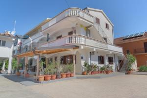 a large white building with potted plants in front of it at Cozy Apartment - 100m from the beach Punta in Pakoštane