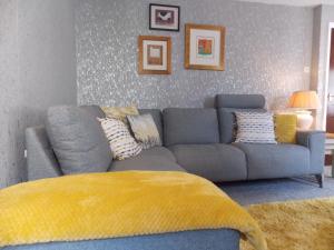 niebieską kanapę w salonie z żółtym kocem w obiekcie Waterloo Cottage w mieście Barnard Castle