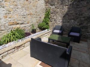a patio with a table and chairs and a stone wall at Waterloo Cottage in Barnard Castle