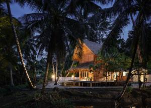 dom w środku palm w nocy w obiekcie Cay's House Batukaras w mieście Batukaras
