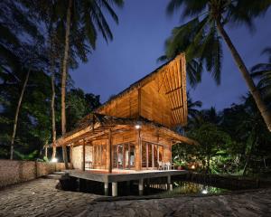 a house with a wooden facade with palm trees at Cay's House Batukaras in Batukaras