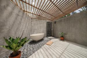 een badkamer met een bad en planten. bij Cay's House Batukaras in Batukaras