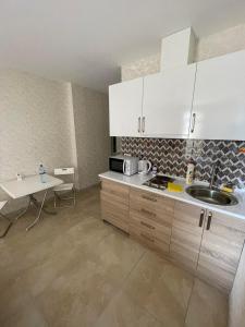 a kitchen with white cabinets and a sink and a table at Europalace Gonio in Gonio