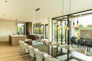 a dining room with a long glass table and chairs at Leie Villa II - by the river with sauna & jacuzzi in Deinze
