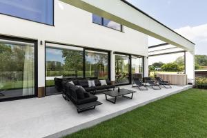 a patio with black furniture and glass windows at Leie Villa II - by the river with sauna & jacuzzi in Deinze