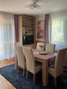 a dining room with a table with chairs and a television at Rózsa nyaralóház in Balatonboglár