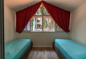 a room with two beds and a window with red curtains at Forest Cottage - middle of forest & near the beach in Golem