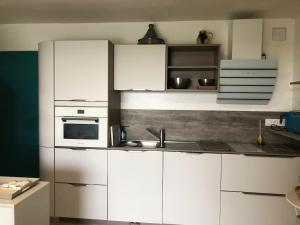 a kitchen with white cabinets and a sink at PARENTHÈSE NATURE in Canet-en-Roussillon