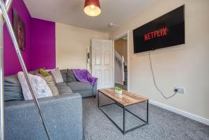 a living room with a couch and a tv on a wall at Coventry Team Accomodation with Private Parking & WIFI in Parkside
