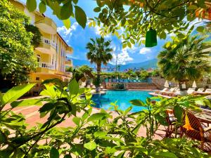 a pool at a resort with chairs and palm trees at Mountain Valley Oludeniz in Oludeniz